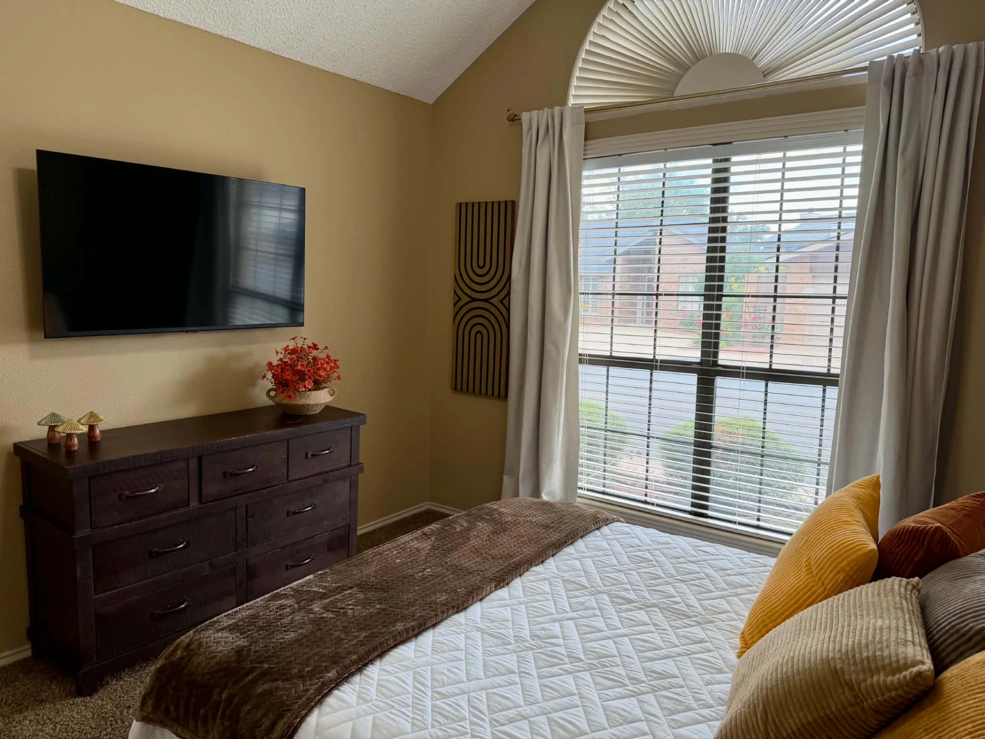 Bedroom 3 — 50" wall-mounted smart TV above a dark wood dresser