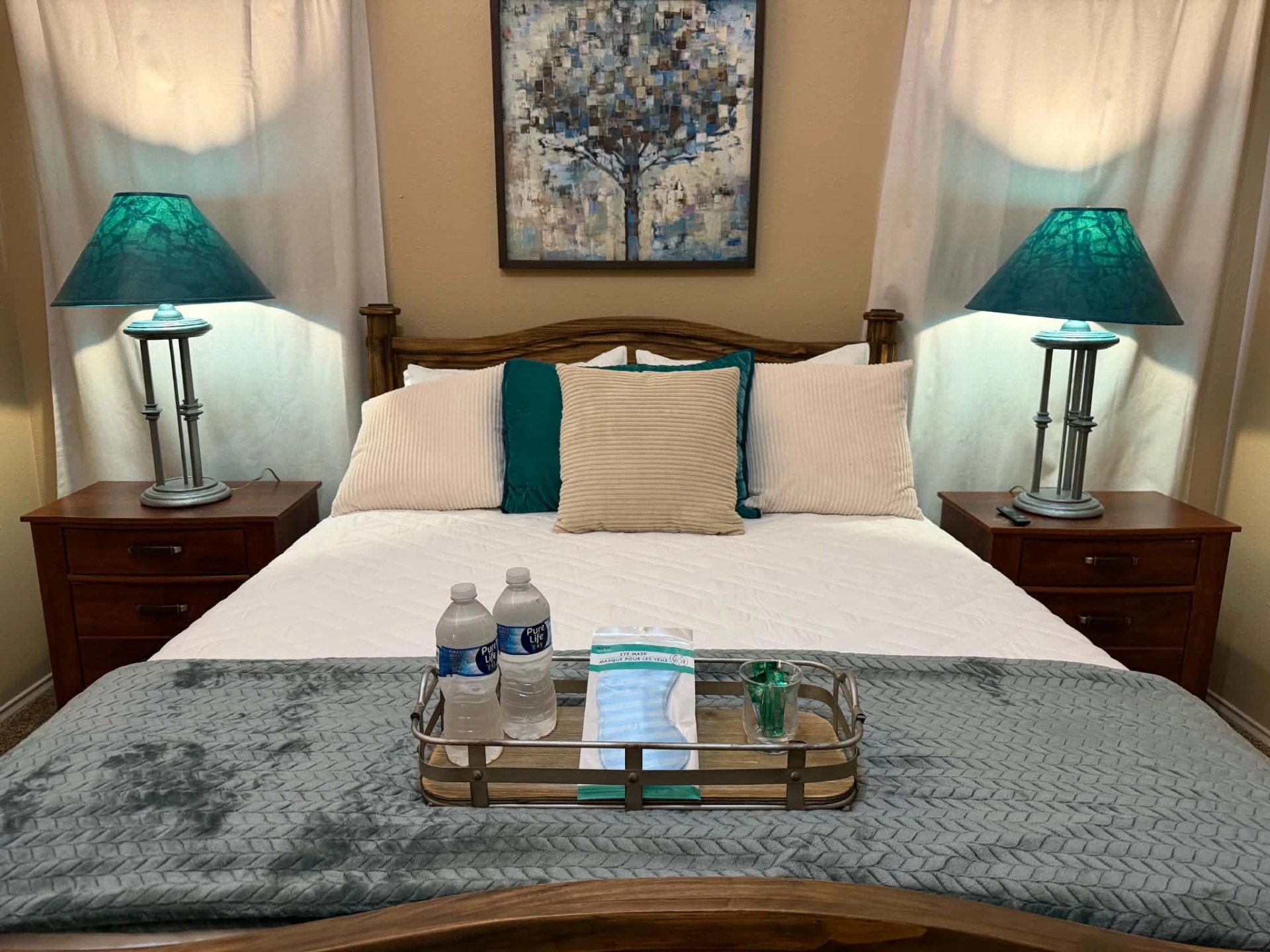 Primary bedroom — queen bed with welcome tray, bottled water and eye masks